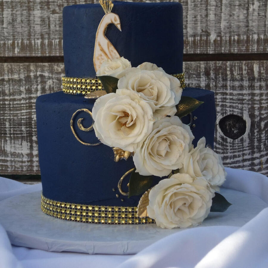 Navy blue tiered cake with white roses and a gold band