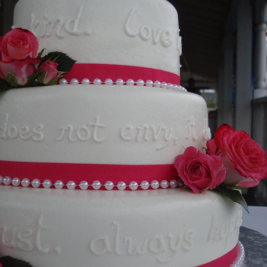 Three-tier white cake with red ribbon bands, red roses and piped lettering