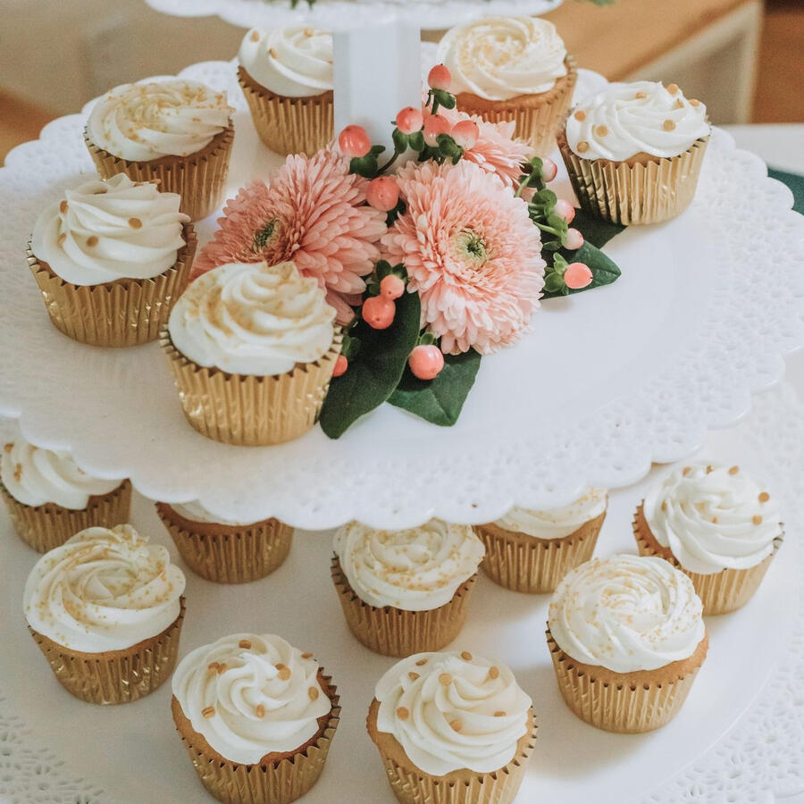 Cupcake tower with pink-frosted cupcakes and fresh flowers
