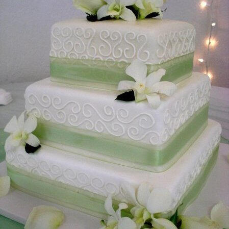 Square tiered white cake with lace piping, sage-green ribbon and white flowers Square tiered white cake with lace piping, sage-green ribbon and white flowers