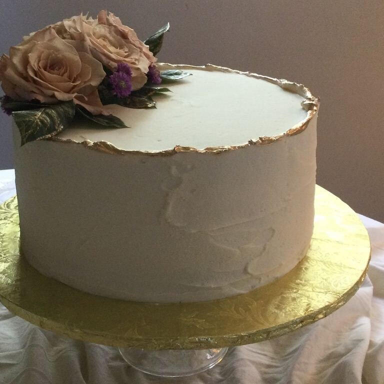 Single-tier white cake topped with a golden rose on a gold cake board Single-tier white cake topped with a golden rose on a gold cake board