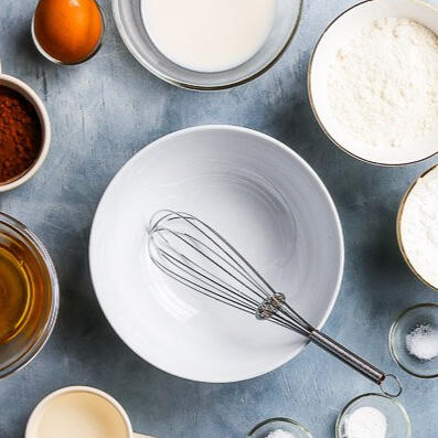 Overhead view of baking ingredients in bowls: flour, eggs, milk and sugar